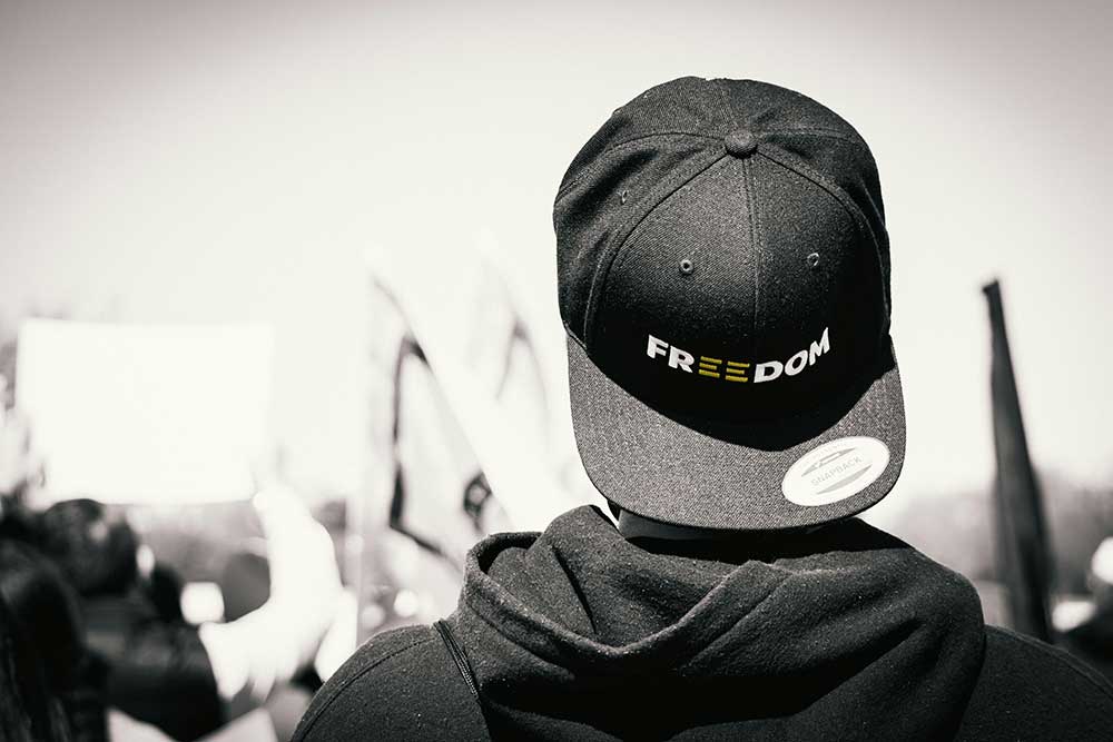 Image of a protestor wearing a hat that says "Freedom"